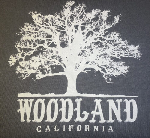 a closeup of a white Woodland logo featuring a silhouette of a large tree