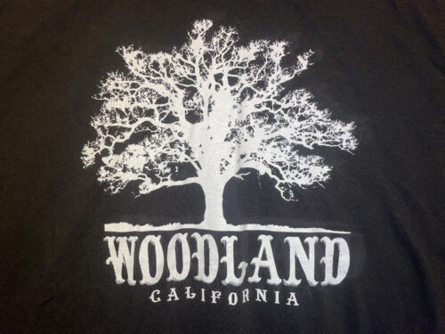 a closeup of a white Woodland logo featuring a silhouette of a large tree